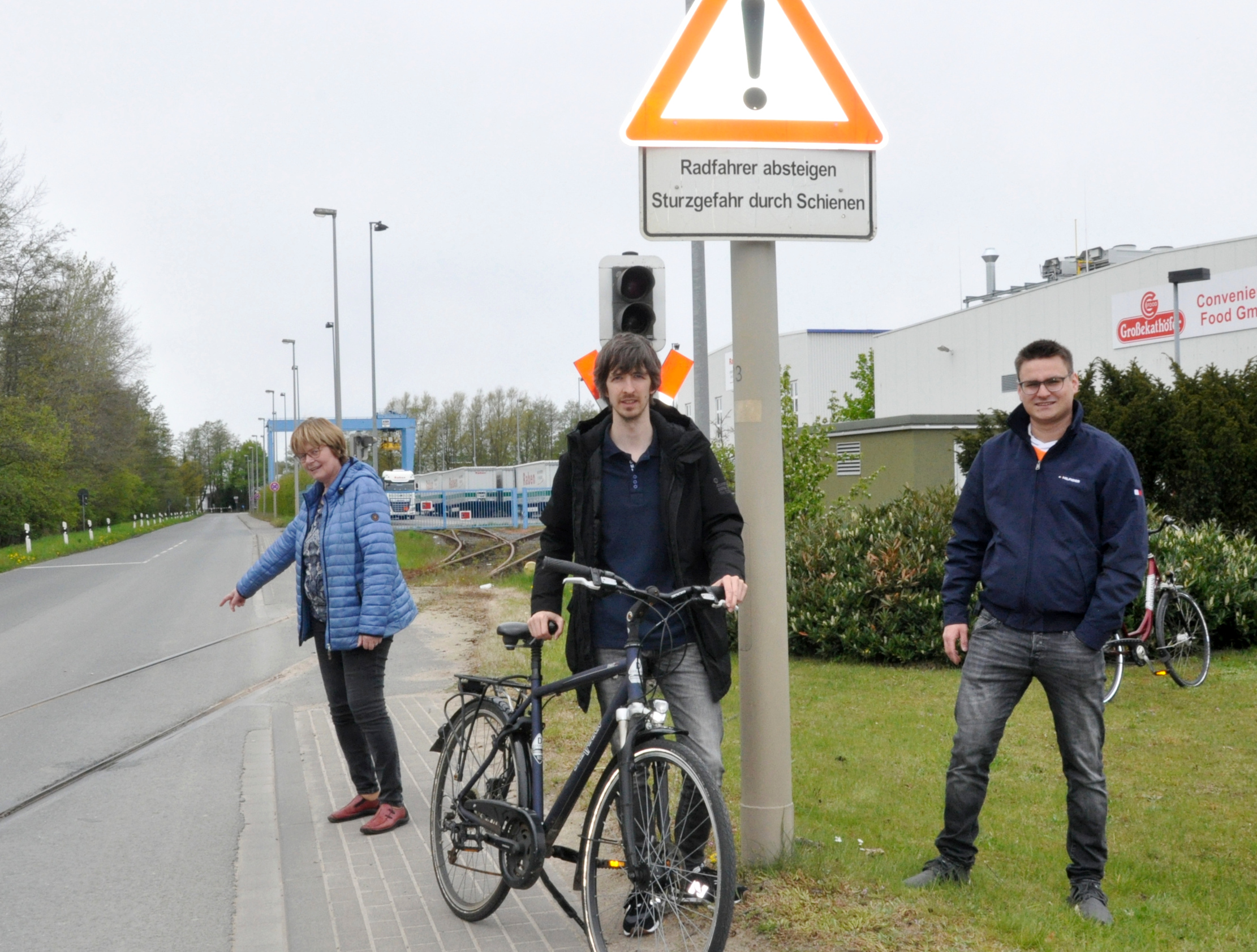 Ingrid Hollenhorst zeigt auf die kritische Stelle der Gleisrillen in der Fahrbahn. Rechts neben ihr Nils Wittenbrink (mit Fahrrad) und Niklas Reimer.